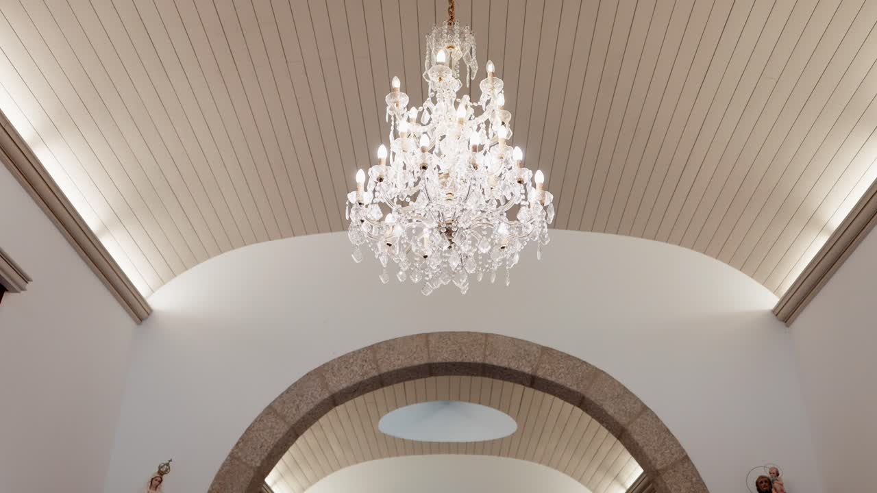 sparkling chandelier suspended under arched wood ceiling with natural light