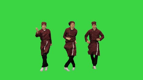 빨간 유니폼을 입은 세 명의 재미있는 셰프 요리사들이 녹색 스크린, 크로마 키에서 녹색 배경에 춤을 추고 있습니다.