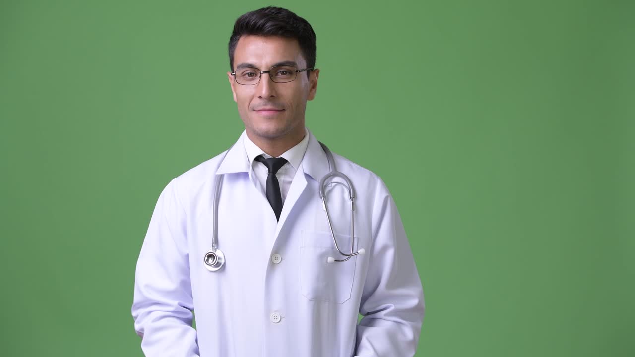 Dokter pria Hispanik muda yang tampan dengan latar belakang hijau.