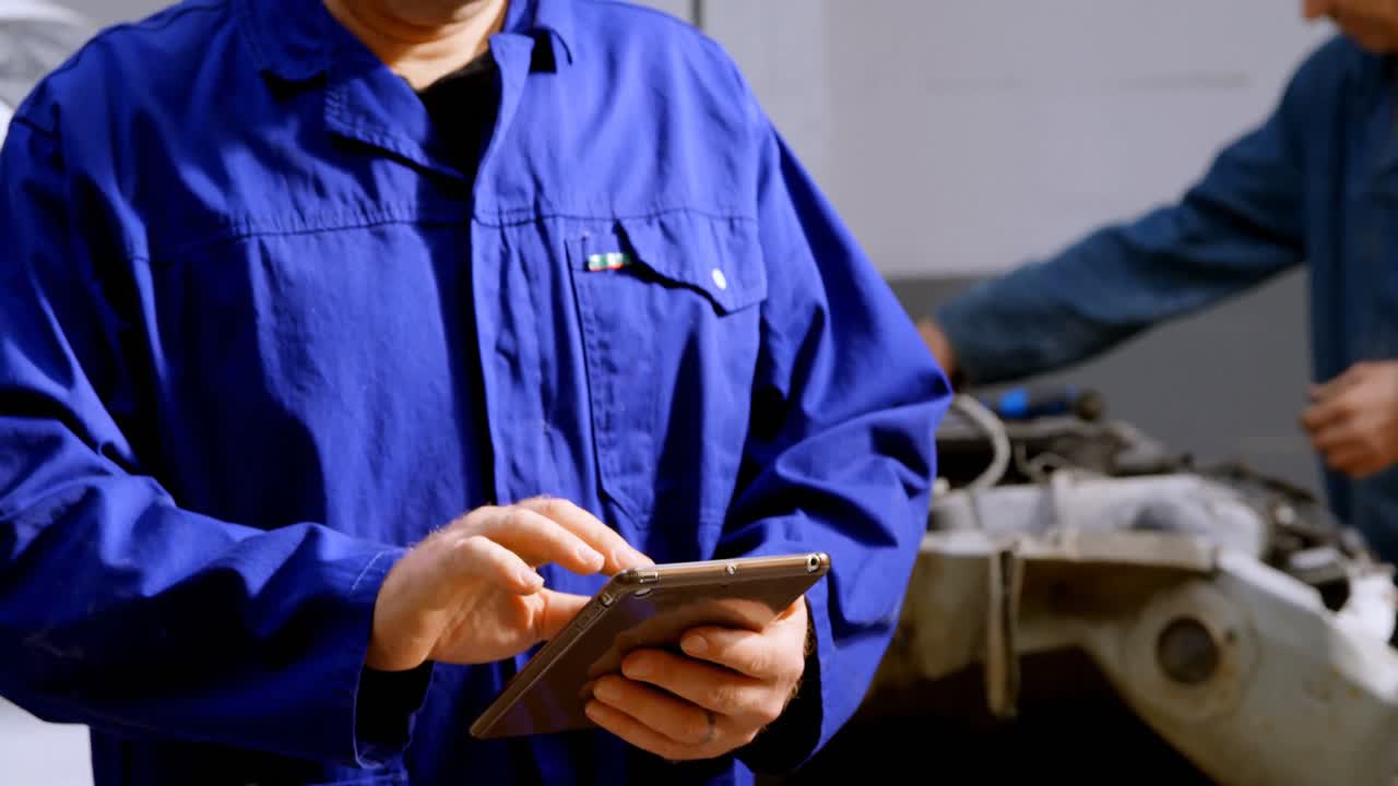 mecánico usando una tableta digital en el garaje de reparación 4k