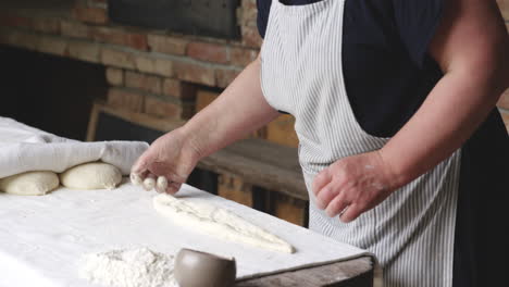 old woman baker putting some flour and oil over a bread dough in sighnaghi, kakheti, georgia