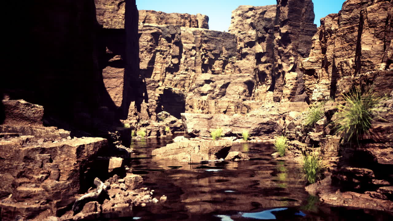 Rocky canyon landscape with tranquil water under clear blue sky