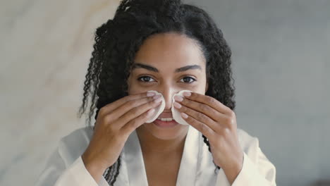 mujer quitando el maquillaje con almohadillas de algodón