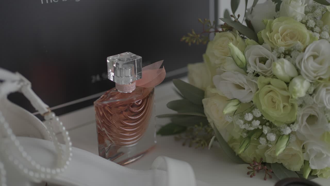 Bottiglia di profumo in vetro accanto a un bouquet da sposa bianco su un tavolo