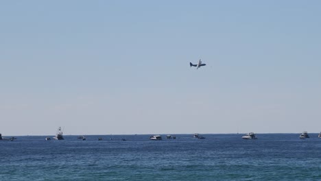 airplane descends over ocean filled with boats