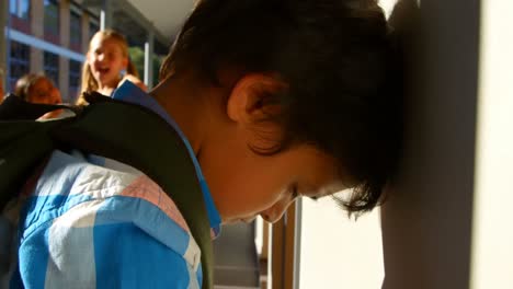 escolares intimidando a un niño triste en el corredor de la escuela primaria 4k