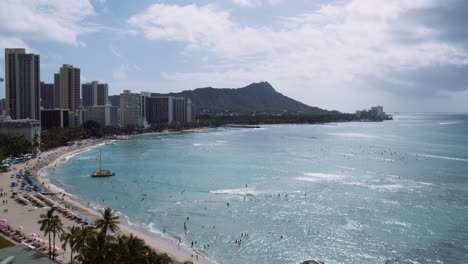 tourists enjoying waikiki beach on sunny day with diamond head in background, hawaii, aerial