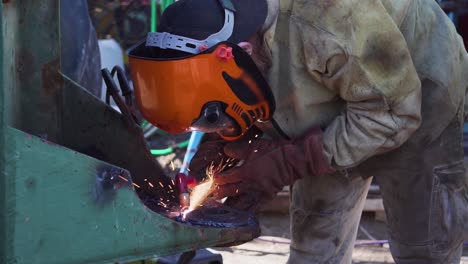 a welder welding a circular metal with a tungsten electrode - close up slowmo