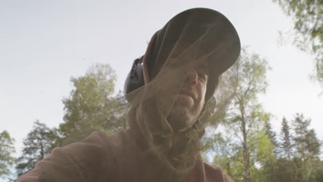 man outdoors in summer wearing mosquito head net against swarming mosquitoes