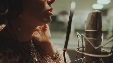close-up of female musician singing into microphone in recording booth