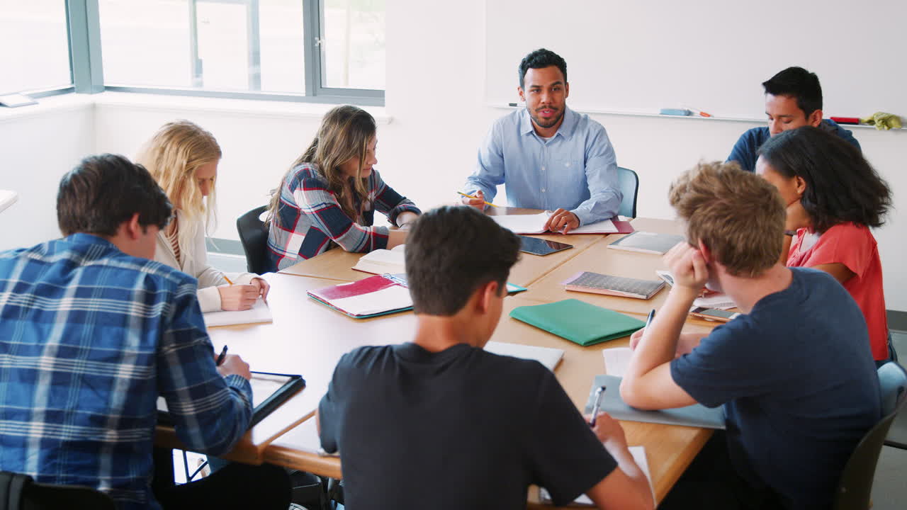 grupo de estudiantes de secundaria con un maestro masculino trabajando en el escritorio