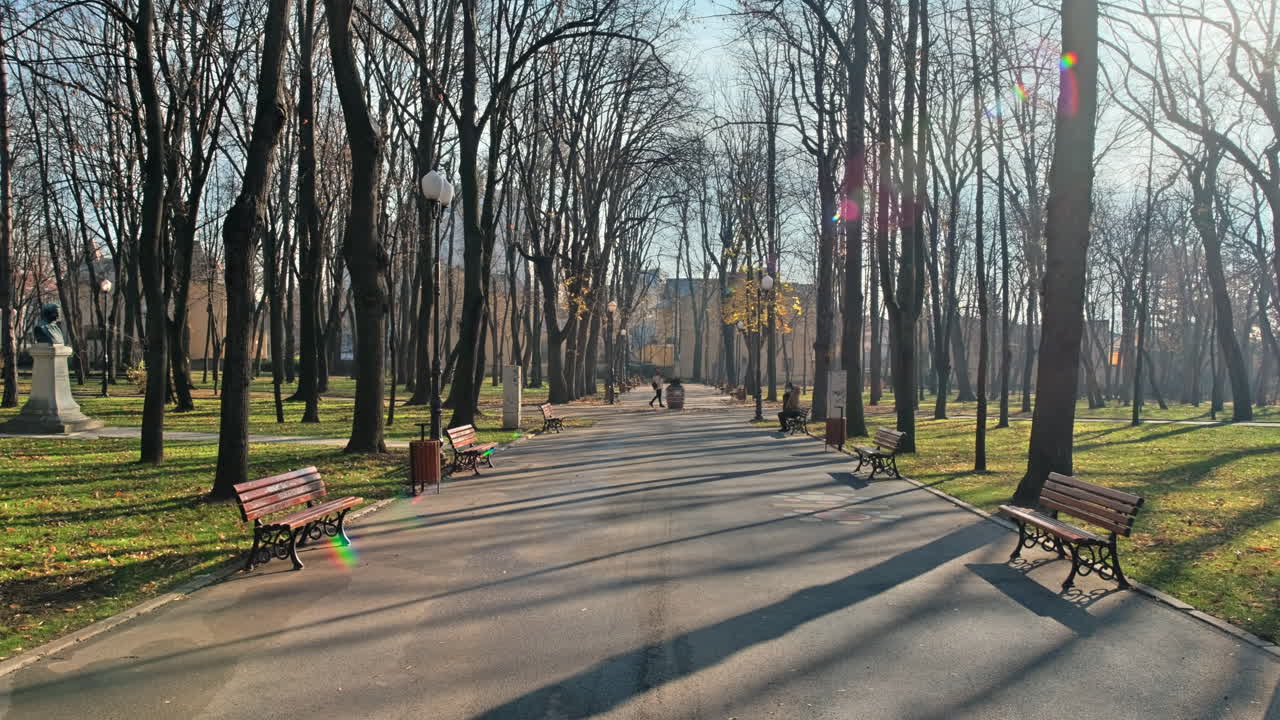 Вид на парк Копоу в Яссах, Румыния. Скамейки, аллея, голые деревья, зеленая трава, люди