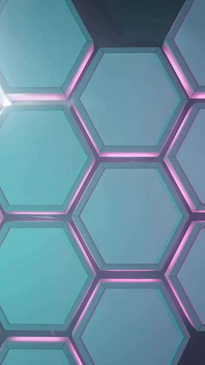 Vídeo vertical: Luzes em movimento do canto superior direito varrendo parede hexagonal no palco, mostrando emendas rosas