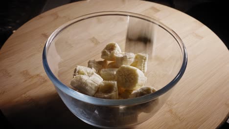 chopped ripe bananas dropping into glass bowl on the table