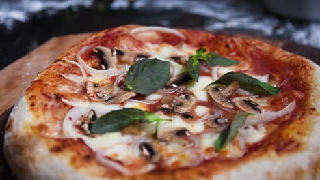 primer plano de una pizza casera de masa fermentada con salsa de albahaca, champiñones, cebolla y queso mozarrella