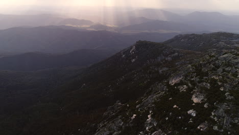 Aerial-of-bouldered-mountains-on-an-overcast-day-with-sun-rays-through-clouds-in-Australia