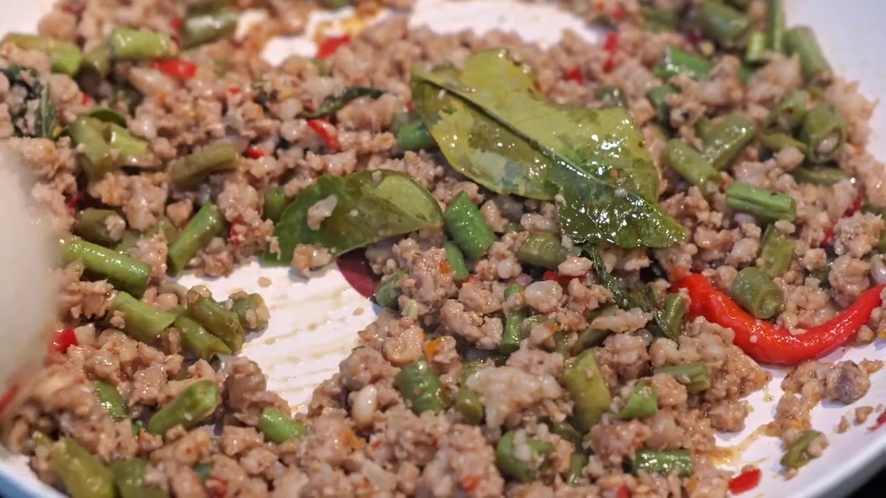 Piatto di carne macinata saltata in padella piccante con fagiolini, peperoncino rosso ed erbe fresche