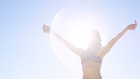 Close-up-of-woman-pouring-sand-running-through-fingers-slow-motion-at-the-beach-with-sun-flare-and-blue-skye