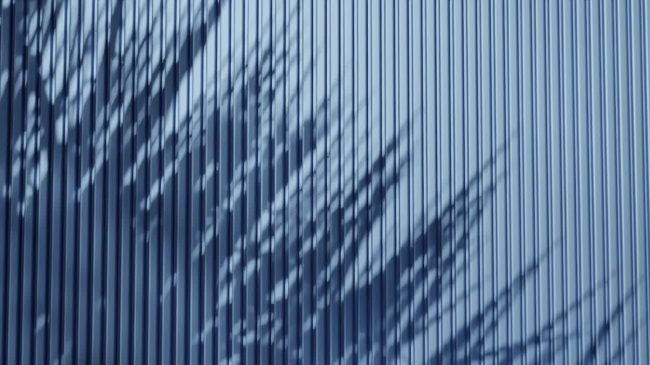 Shadow of palm leaves on vertical blue corrugated metal wall. Abstract natural light and line pattern background. Design for wallpaper, banner, postcard, greeting card, poster, vertical