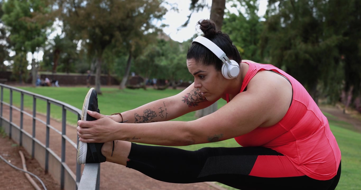 Woman Stretching Leg on Metal Rail in Park