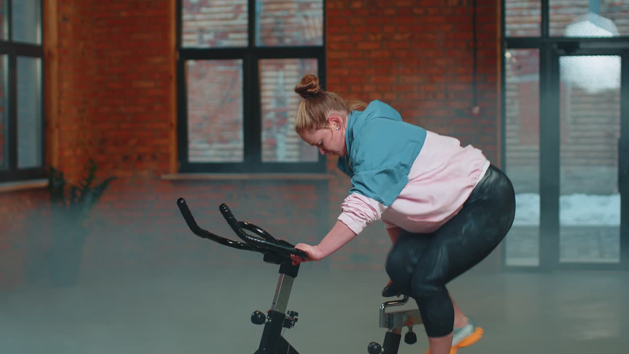 Woman performs aerobic endurance training workout cardio routine on the simulators cycle training