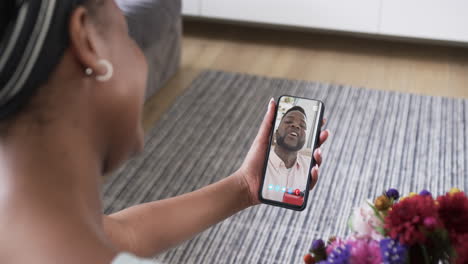 Biracial-woman-holding-smartphone-with-biracial-man-with-gift-on-screen