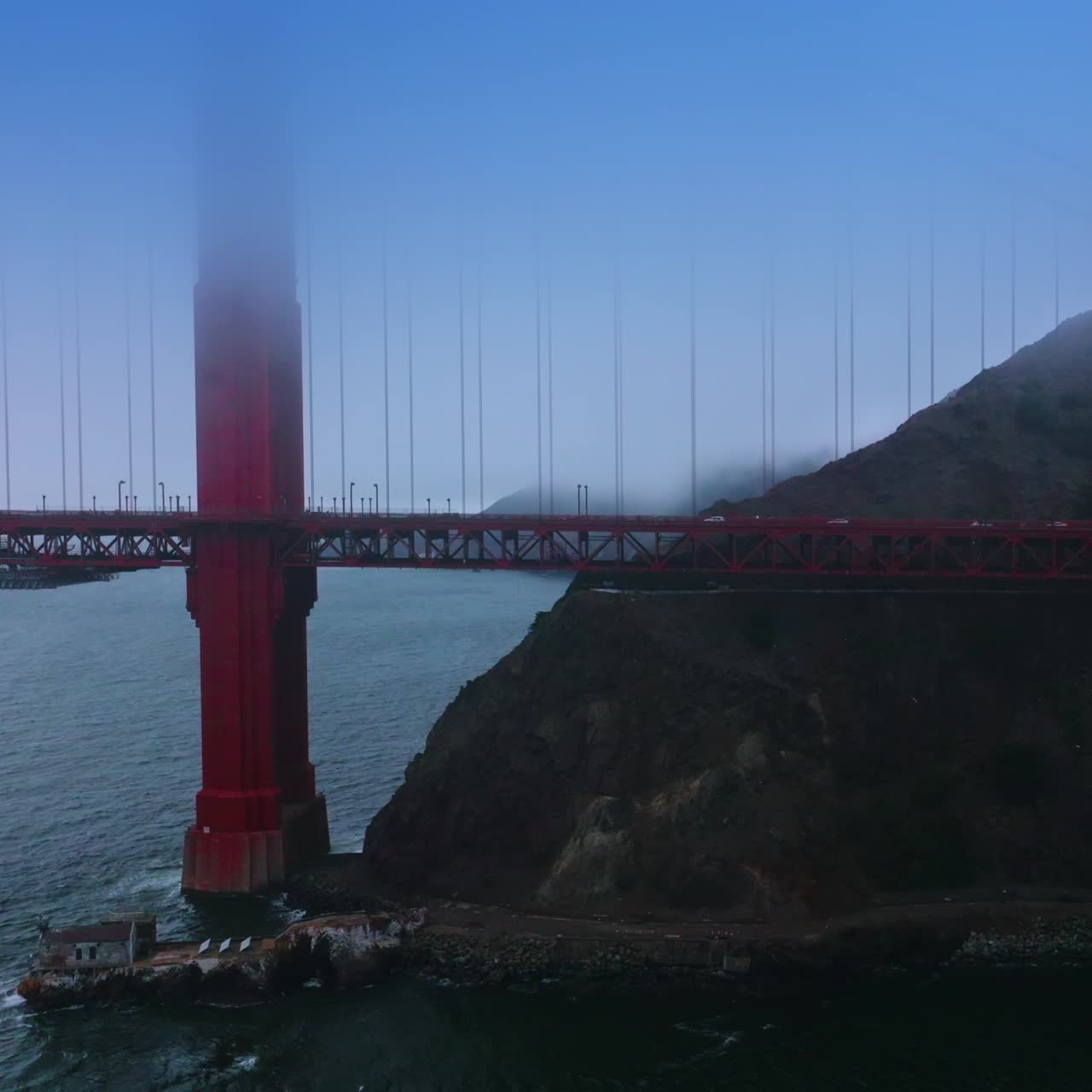 Well recognized supports of beautiful Golden Gate Bridge near the rock. Cars going by the bridge. Amazing Landmark of San Francisco, California, USA