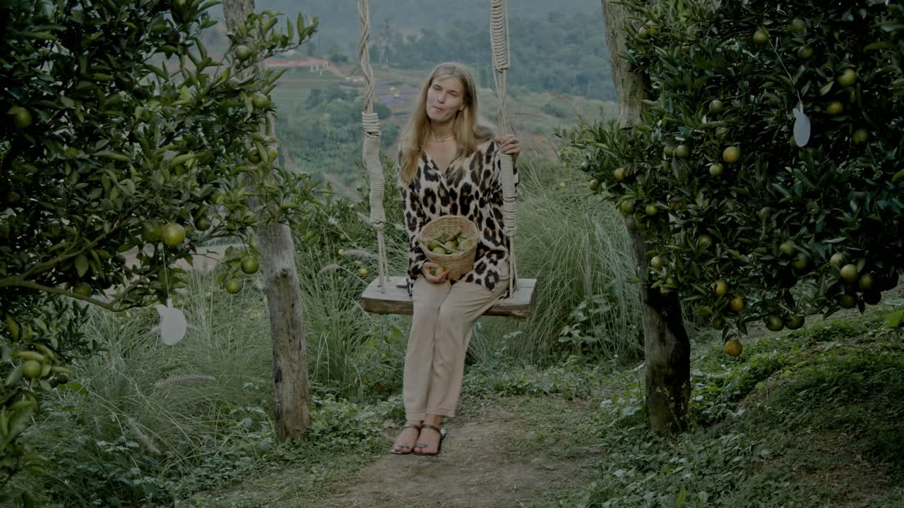 Woman sitting on a swing in an orange grove