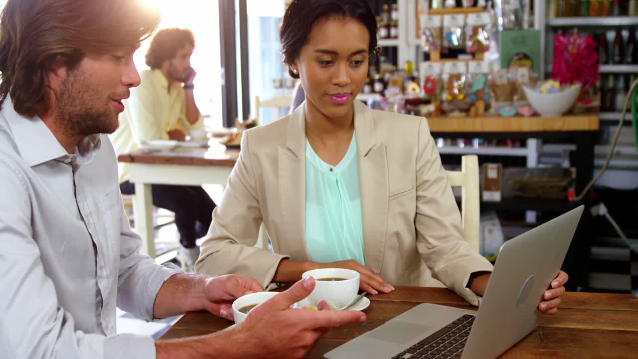 hombres de negocios usando una computadora portátil mientras tienen una taza de café