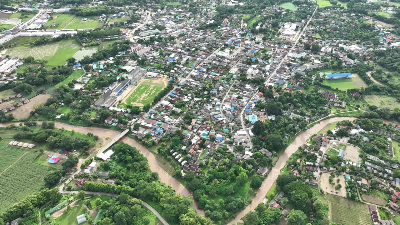 A small town in northern thailand, showing lush greenery, roads, and buildings, aerial view
