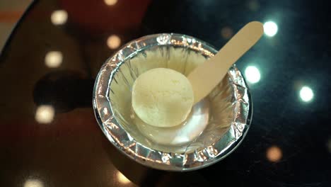 colpo alla testa dei più famosi dolci bengalesi o indiani: rasgulla in una ciotola di carta con un cucchiaio di legno