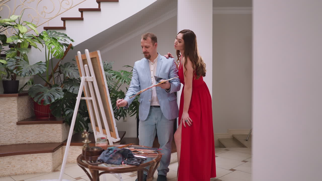 여성은 예술의 마스터를 따뜻한 포옹으로 감싸고, 여성 모델은 독특한 유대감을 형성하고, 예술 작업실에서 예술적 여정을 공유합니다.