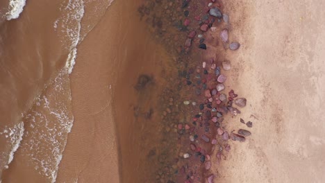 aerial top down view of calm ocean waves crashing into beach at day