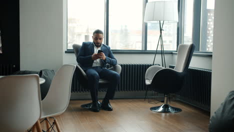 hombre de negocios que usa un teléfono inteligente en una oficina moderna