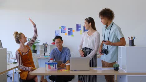 vista frontal de jóvenes empresarios de raza mixta trabajando en una computadora portátil y sonriendo juntos 4k