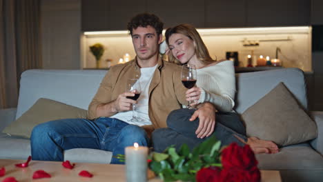 loving family clinking glasses at romantic home date. spouses relaxing on couch
