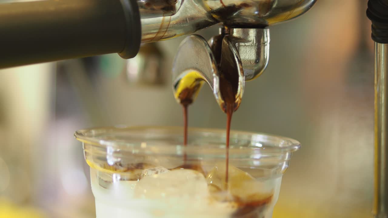 Espresso being poured over ice in a plastic cup
