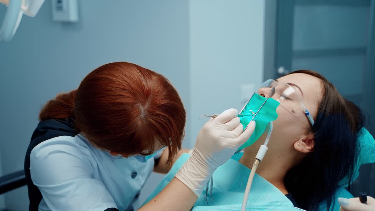 Stomatology treatment in dentistry. Stomatologist treats patient's teeth. Dentist cures teeth of young woman in modern stomatology clinic.