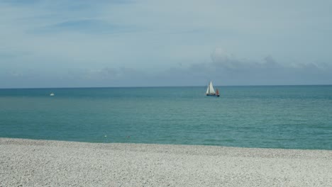 ocean view with sailboat and pebble beach