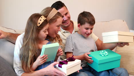 happy young family sitting on sofa with birthday presents