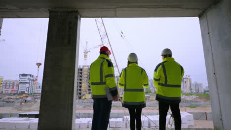 three civil engineers are viewing construction site of residential or nonresidential building