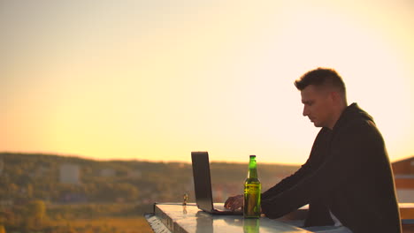 hombre hipster con una computadora portátil en el borde del techo. freelancer en el trabajo. internet móvil inalámbrico. él trabaja en internet.