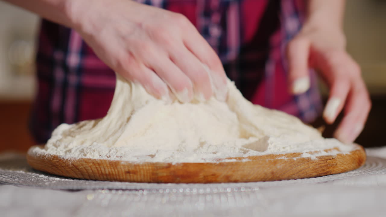 제빵사의 손이 얕은 피사계 심도 4k 비디오로 피자 반죽 비디오를 반죽합니다.