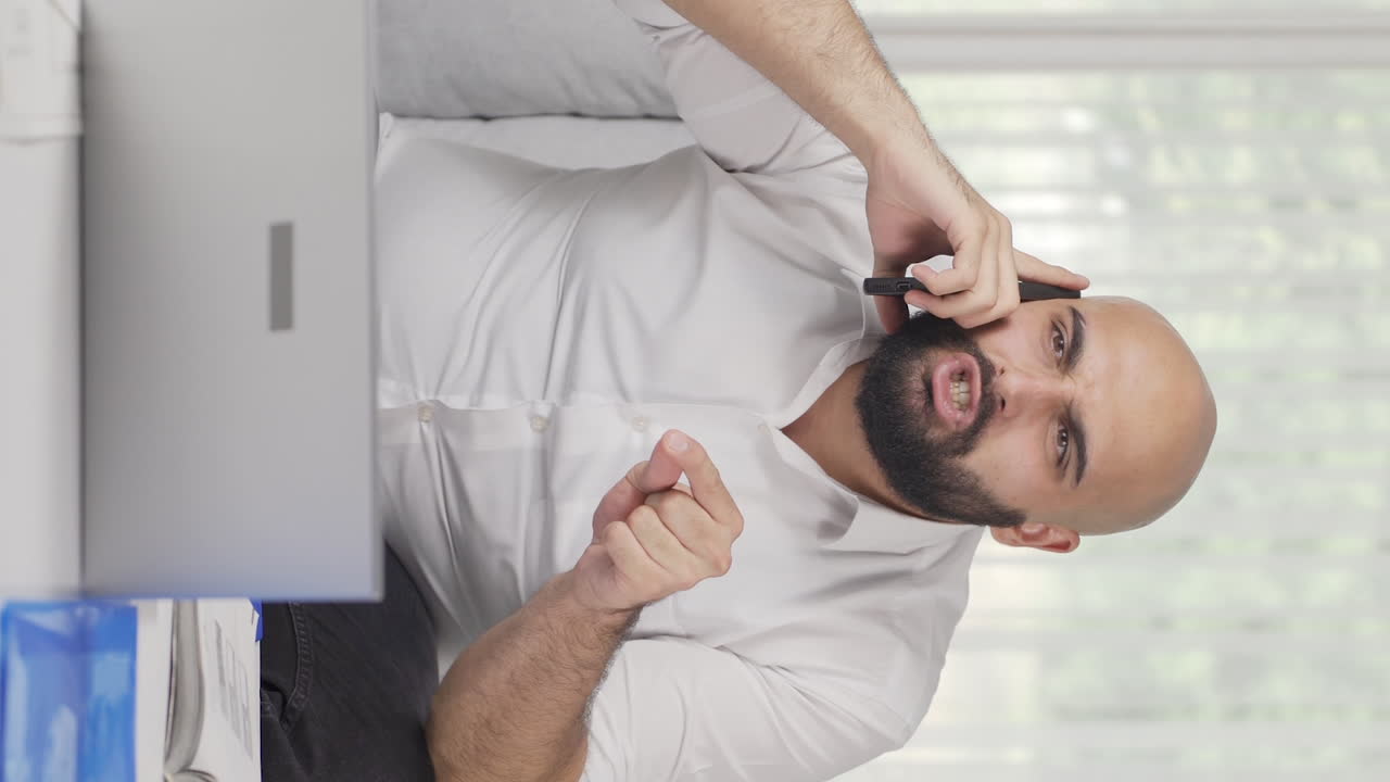 Vertical video of Home office worker man phone angry performs business call.