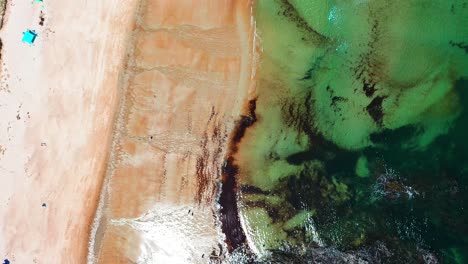 drone flying high for a bird’s-eye aerial view looking down on maine’s saco beaches. crowds gather on sandy shores near vacation homes, with the atlantic ocean’s waves crashing along lively coastline