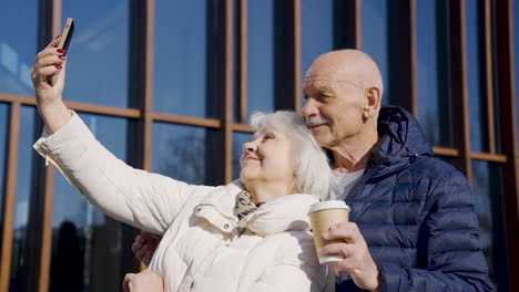 senior couple making a selfie with smartphone in the street on a winter day