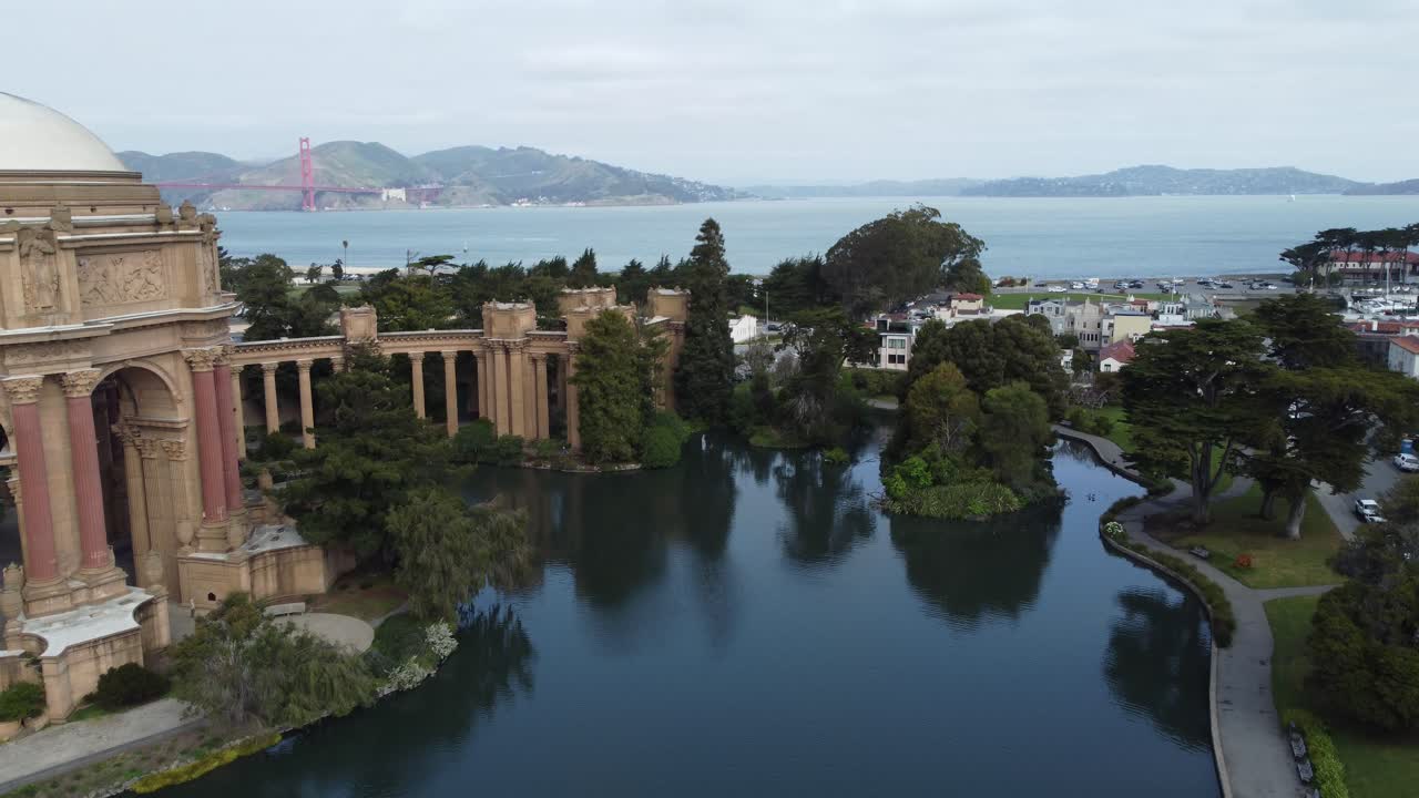 Drone Flying Over The Lagoon Of The Palace Of Fine Arts Slowly Approaching The San Francisco Golden Gate Bridge.