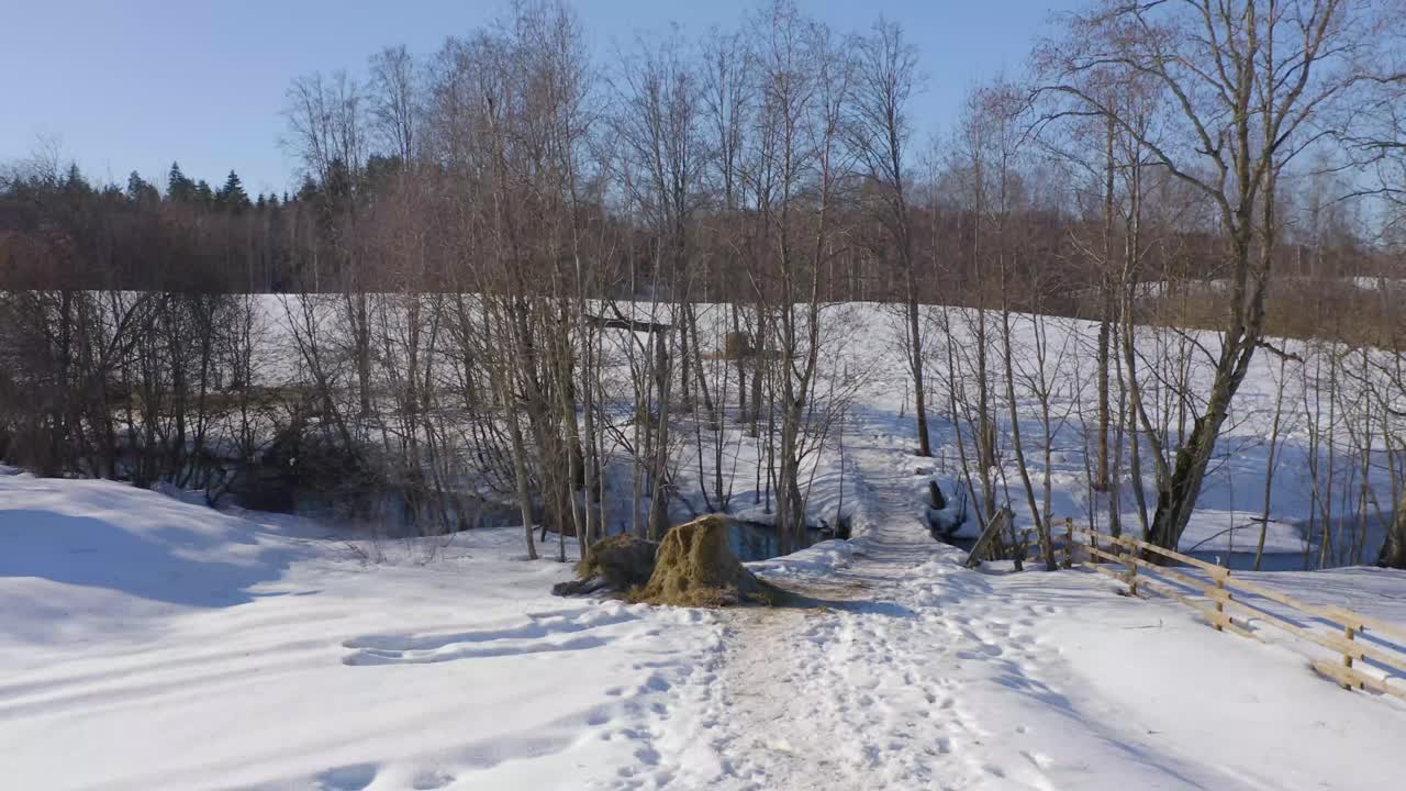 눈 덮인 자연 속에서 작은 다리의 낮은 드론 비디오