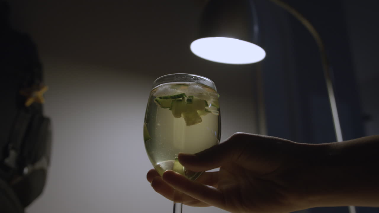 primer plano de ángulo bajo de una persona recogiendo un vaso de sangría, iluminación tenue y melancólica