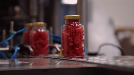 Rote-Gummiartige-Multivitaminpräparate-In-Flaschen-Abgefüllt-Und-Auf-Dem-Förderband-–-Automatisierter-Prozess